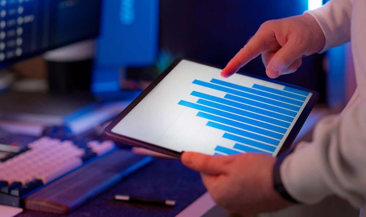 Home Business professional analyzing bar chart on tablet in office setting, highlighting data insights.