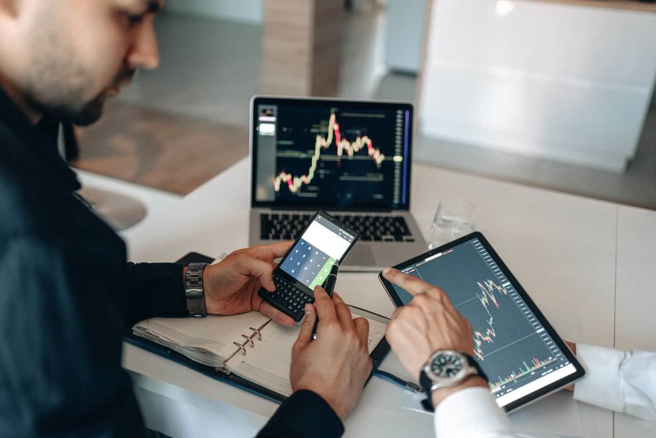 Services Two professionals examining financial data on digital devices at a modern office.